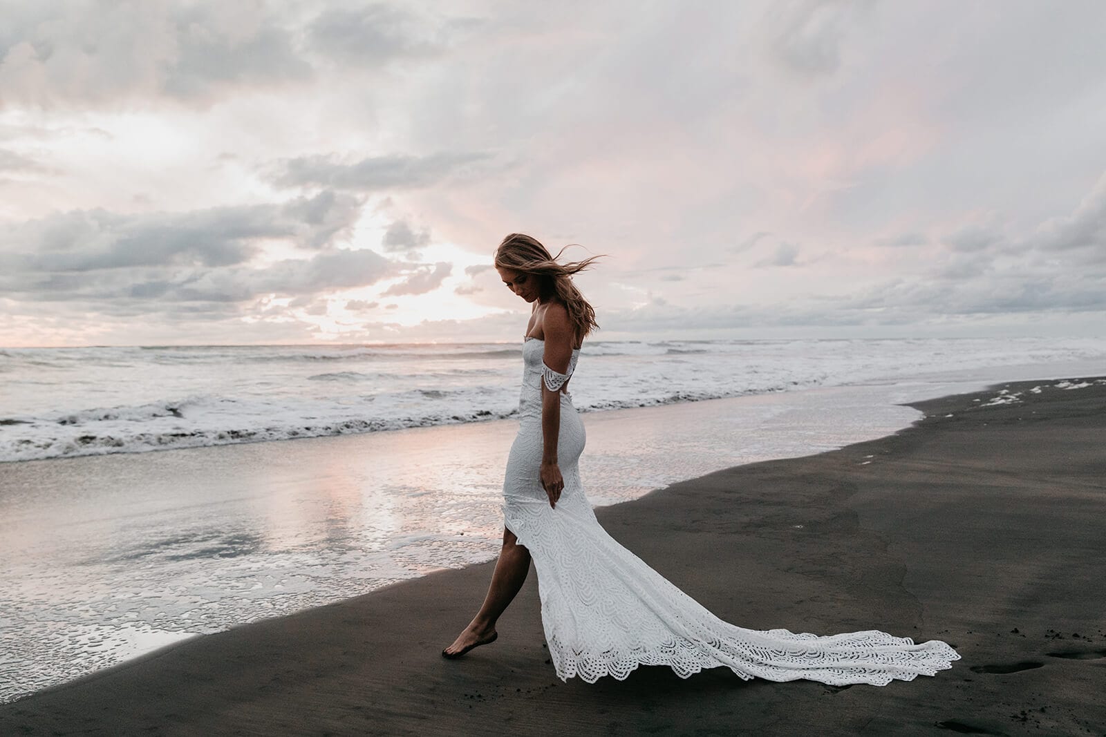 Blonde bride wearing Grace Loves Lace Paloma Gown on beach