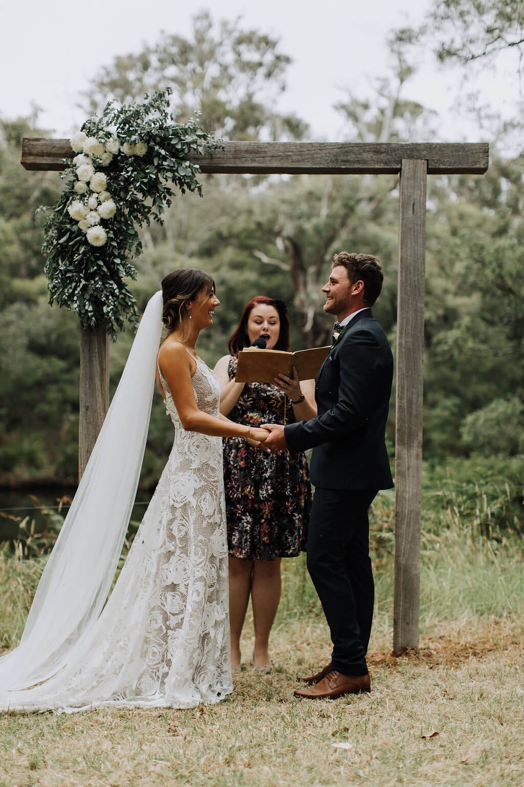 Side shot of bride wearing Grace Loves Lace Rosa Gown holding hands with groom