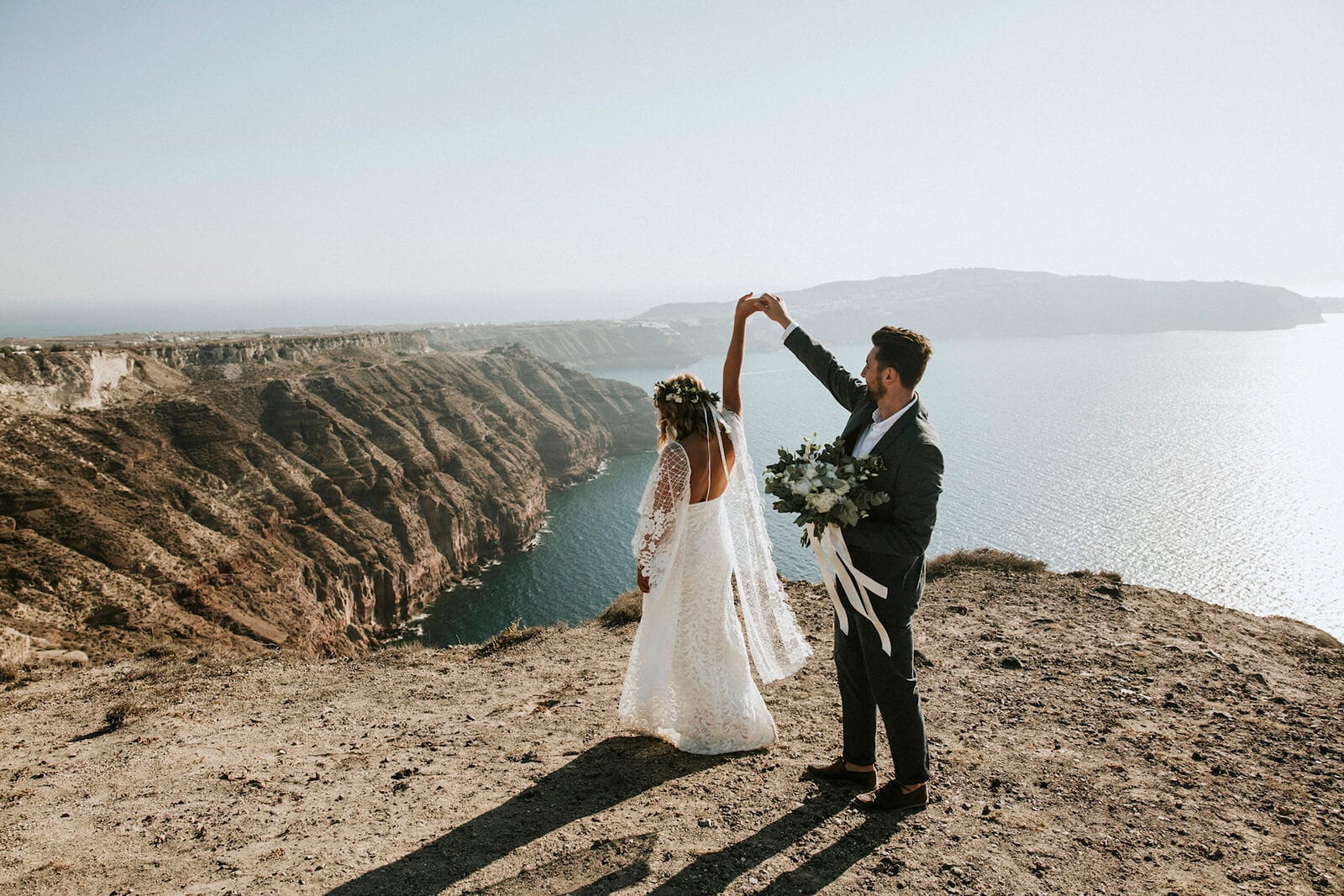Bride wearing Grace Loves Lace Verdelle 2.0 Gown dancing with groom on seaside cliff