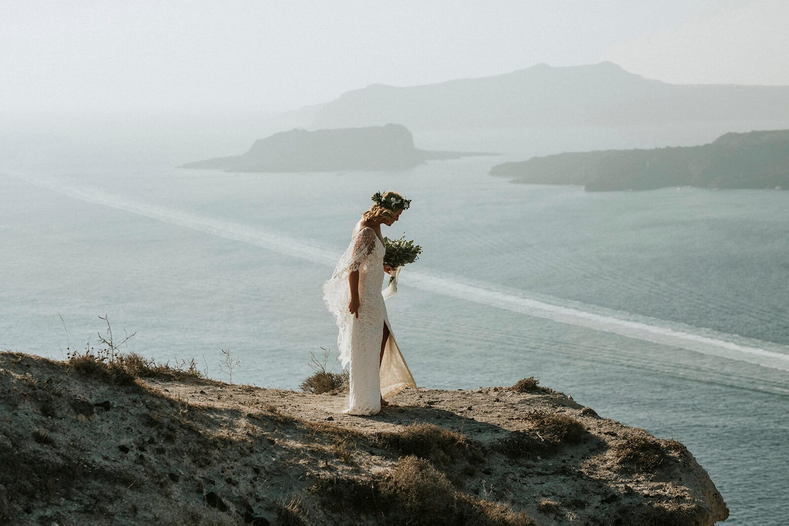 Bride wearing Grace Loves Lace Verdelle 2.0 Gown holding bouquet standing on seaside cliff