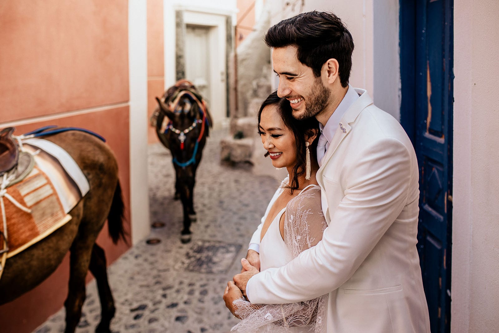 Brunette bride wearing Grace Loves Lace Arlo Gown being embraced by groom watching donkeys walk past