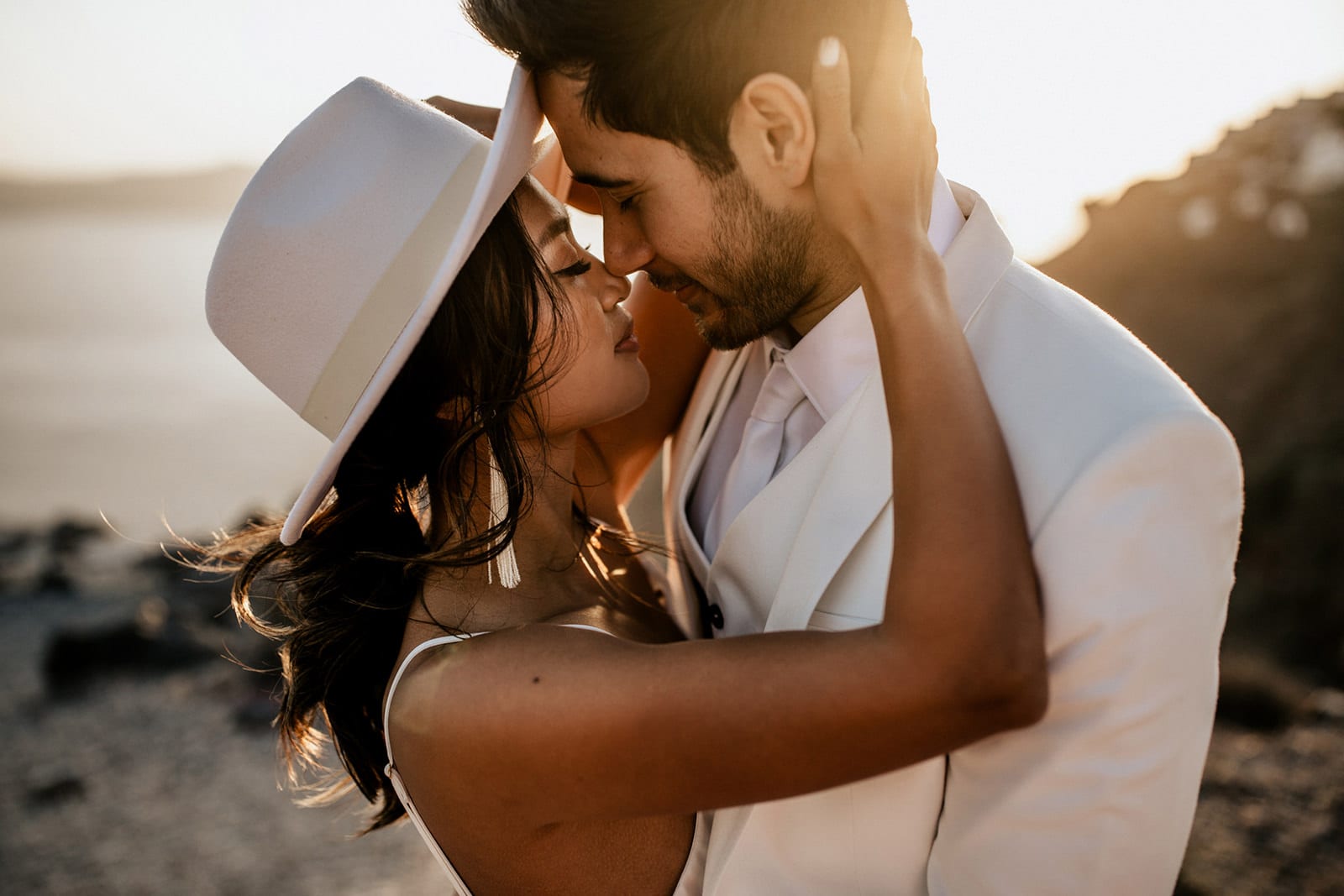 Brunette bride wearing Grace Loves Lace Arlo Gown and hat embracing groom