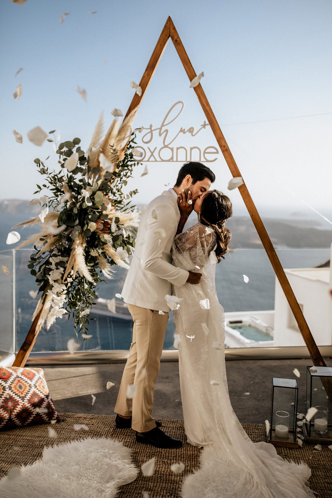 Brunette bride wearing Grace Loves Lace Arlo Gown kissing groom with white flower petal shower