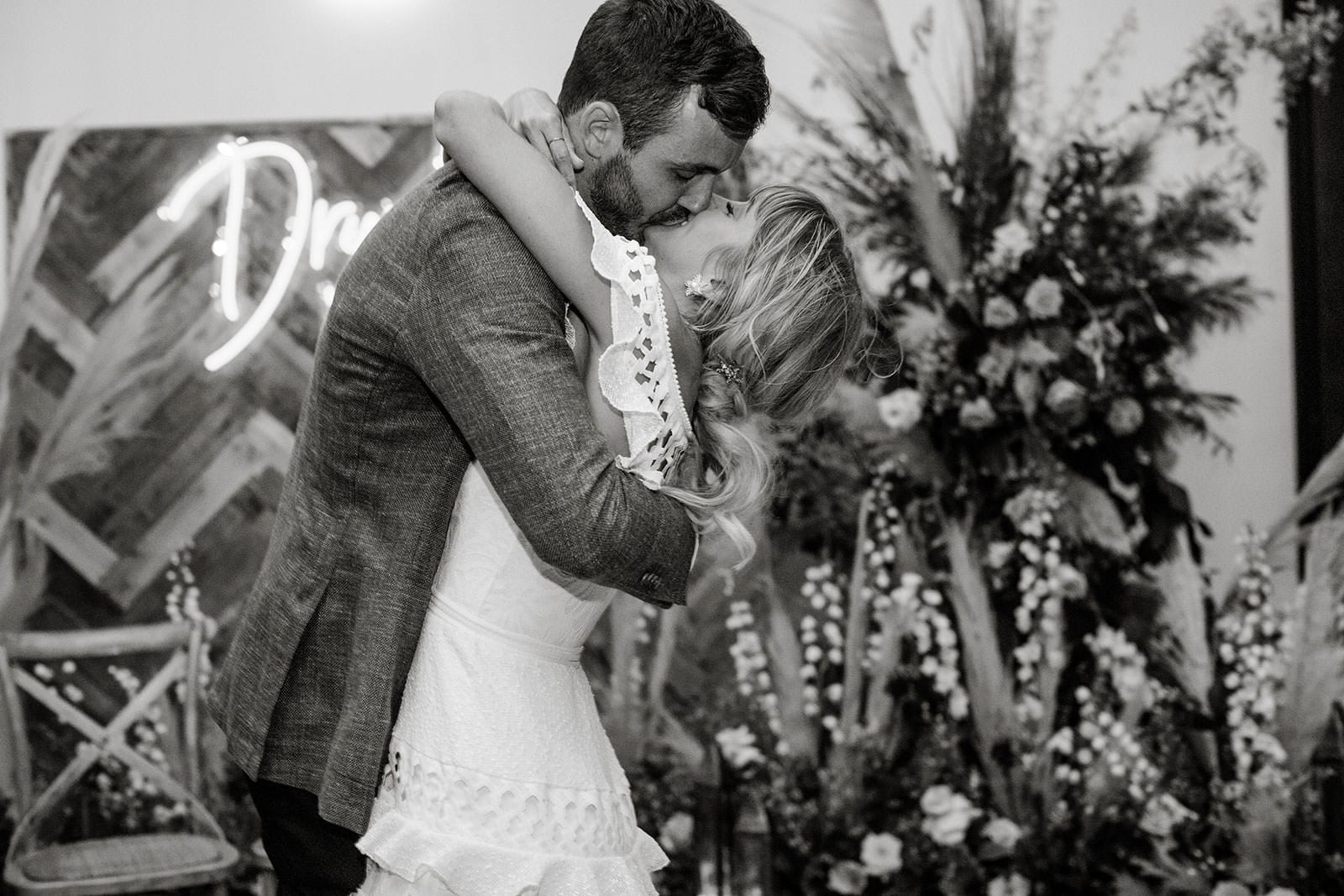 Black and white shot of bride wearing Grace Loves Lace Coco Gown kissing groom