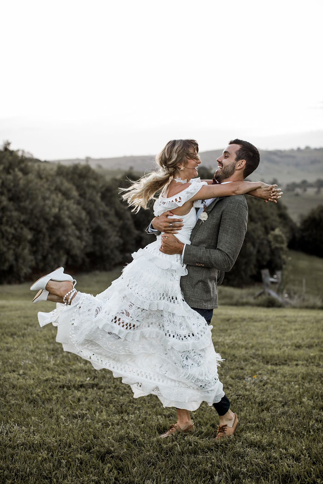 Blonde bride wearing Grace Loves Lace Coco Gown being held by groom
