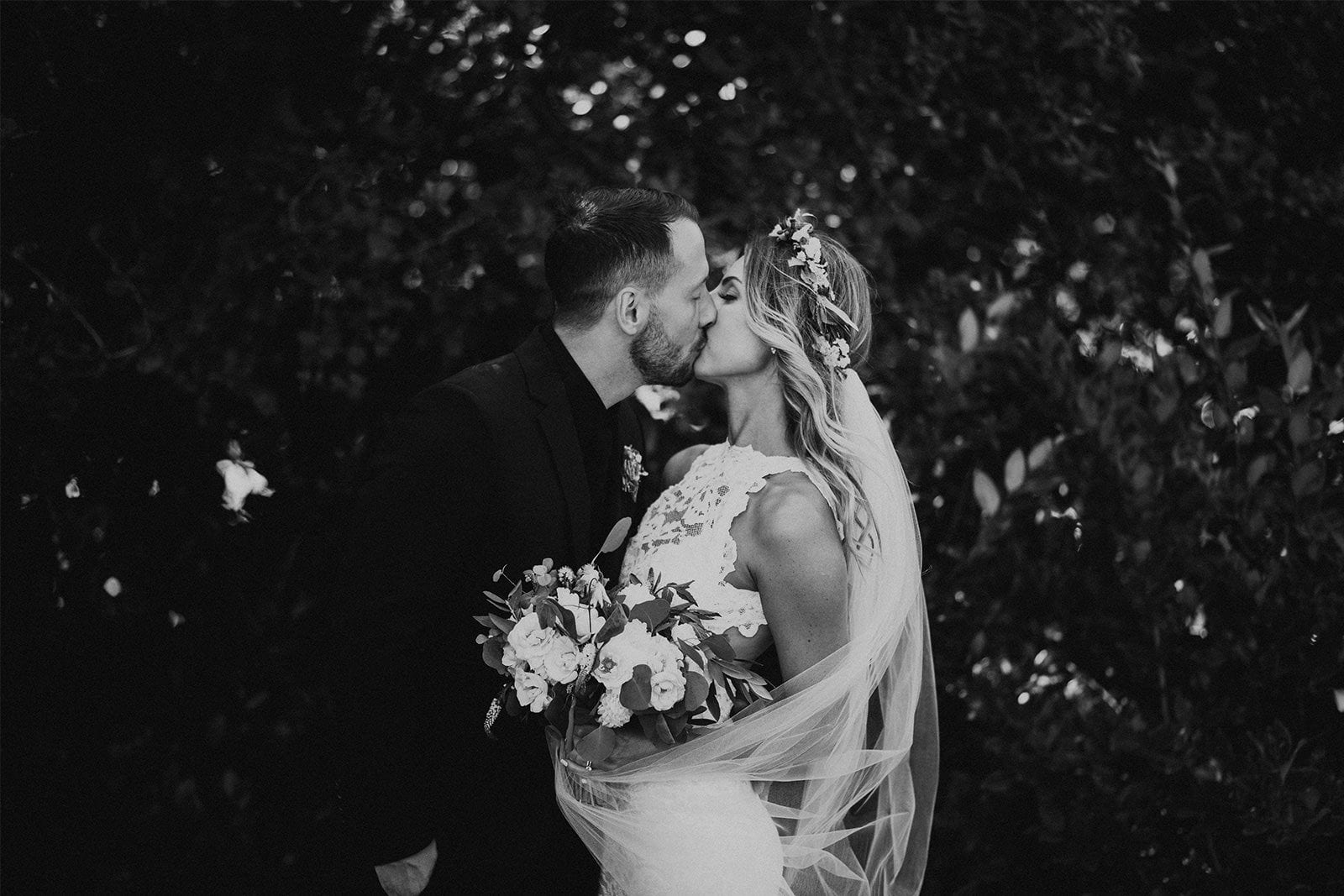 Black and white shot of bride wearing Grace Loves Lace Alexandra Gown kissing groom